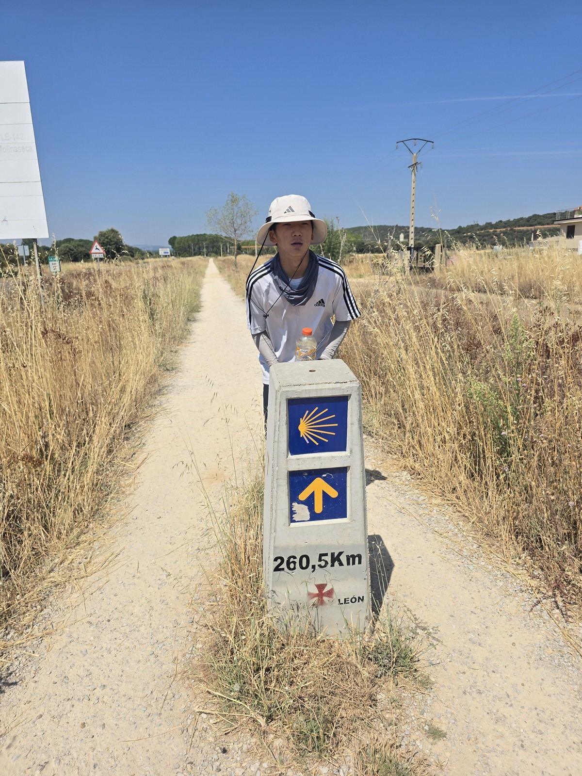 흰 표석에 260,5Km 라고 새겨진 조가비 화살표 표지. 옆으로 흙길이 이어진다
