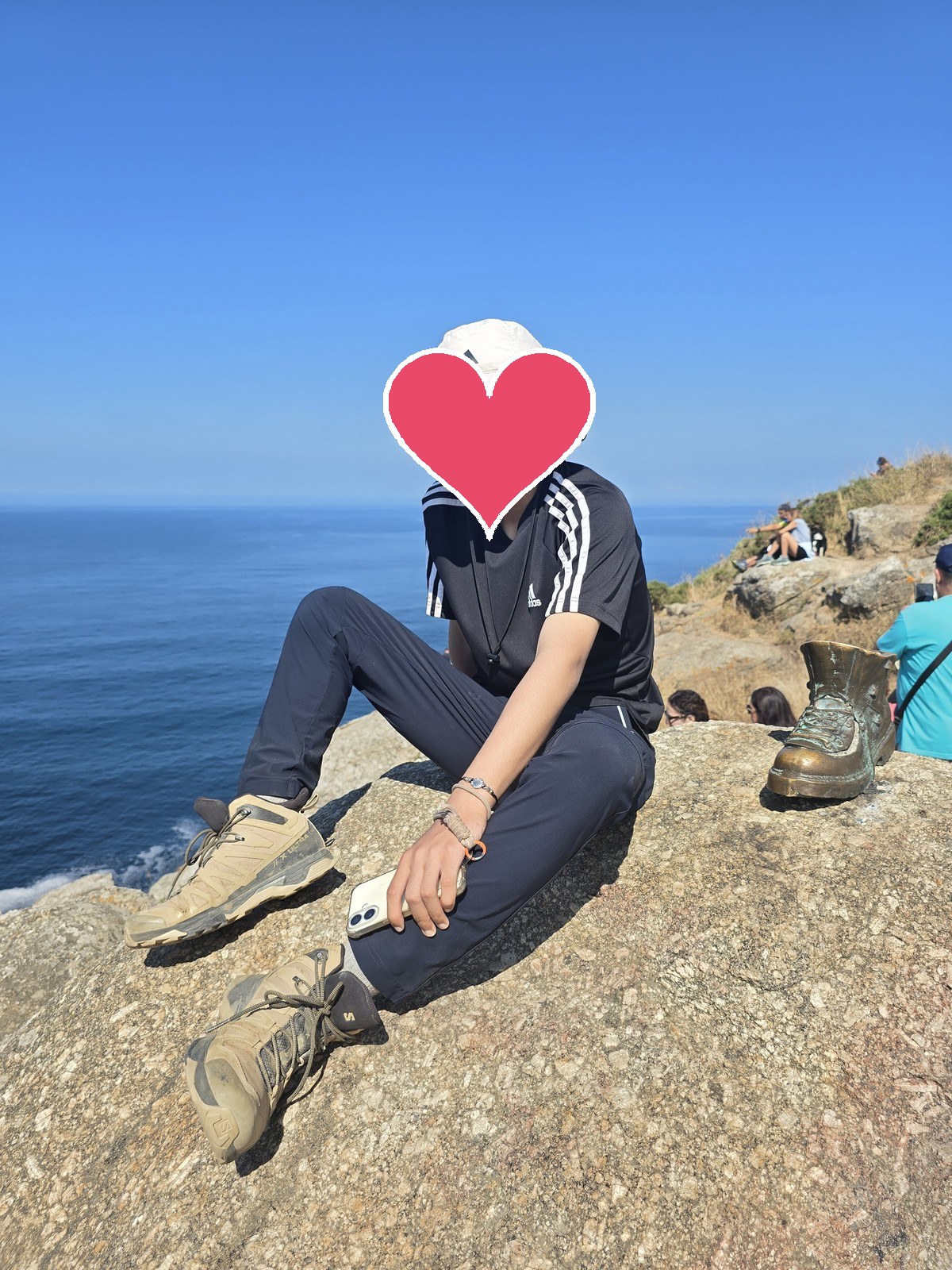 곶 끝 바위에 앉은 사람 옆에 청동으로 만든 등산화 조형물이 놓여 있다