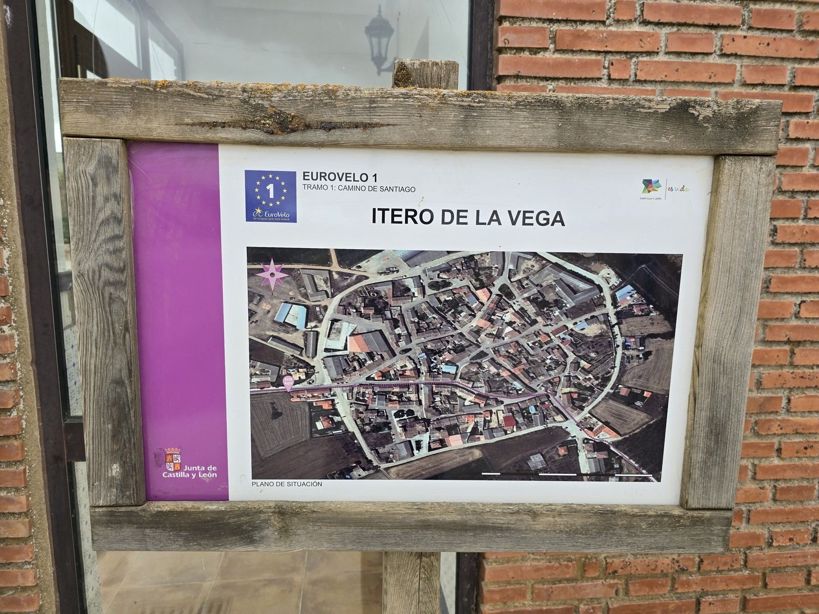 벽돌 벽에 붙인 나무틀 안내판. 위성사진 지도와 ITERO DE LA VEGA 라는 글자가 인쇄돼 있다