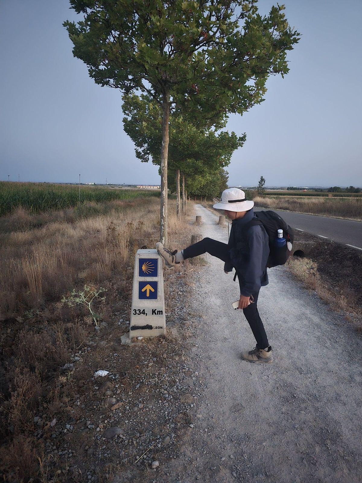 어스름 속 표석에 걸터앉은 사람. 334 Km 라는 숫자가 새겨져 있다