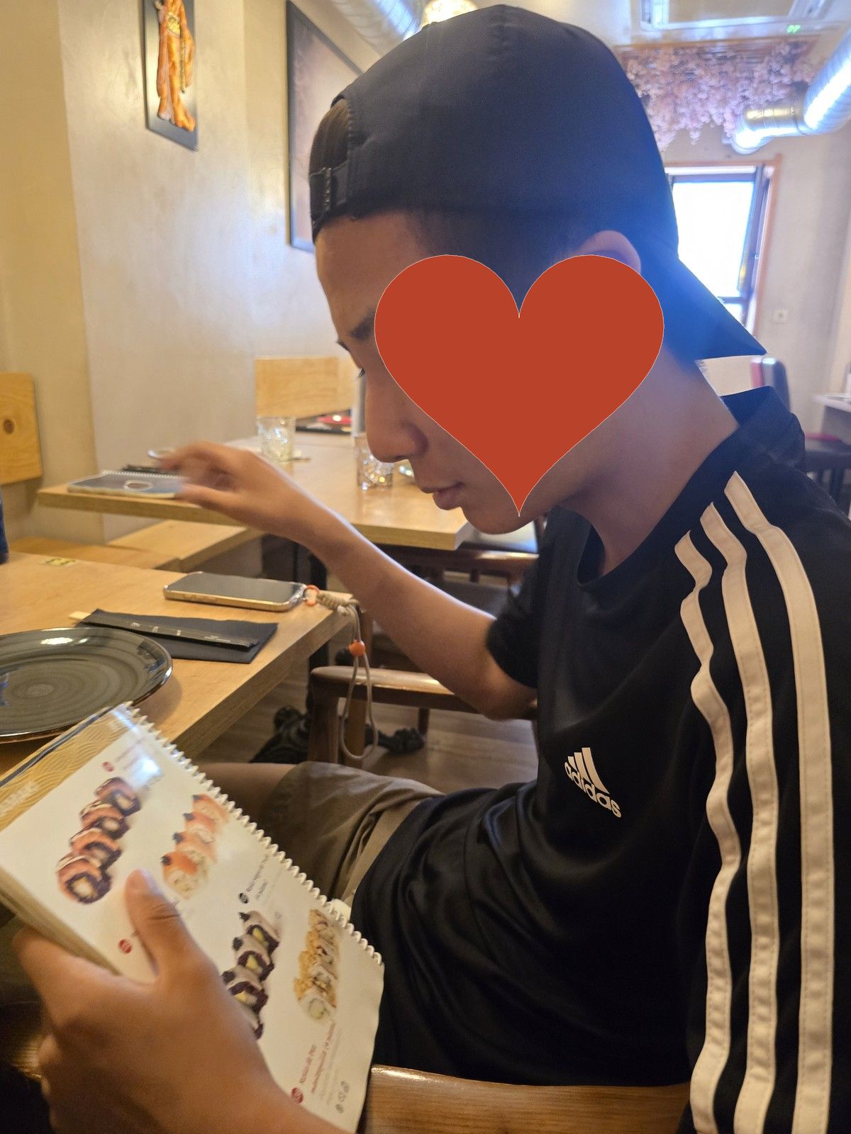 식당 안에서 메뉴판을 골똘히 들여다보는 순례자. 얼굴은 붉은 하트로 가려져 있다