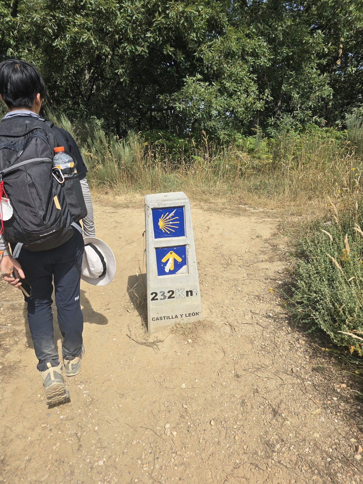 흙길 옆에 선 콘크리트 이정표. 조가비와 화살표 표지 아래 '232Km CASTILLA Y LEÓN'이라 적혀 있다