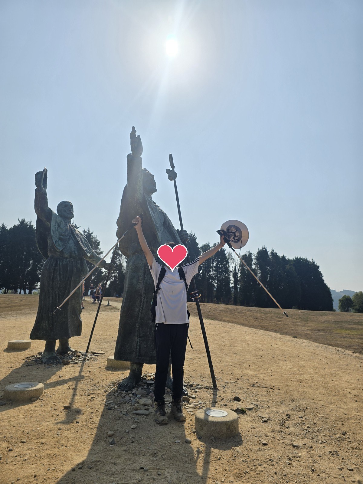순례자가 스틱을 든 두 팔을 하늘로 들어 올리고 몬테 도 고소의 청동 순례자상 앞에 서 있다