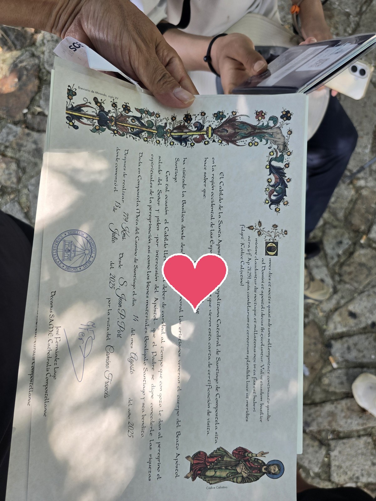 라틴어로 쓰인 순례 증명서 콤포스텔라를 두 손으로 펼쳐 들고 있다